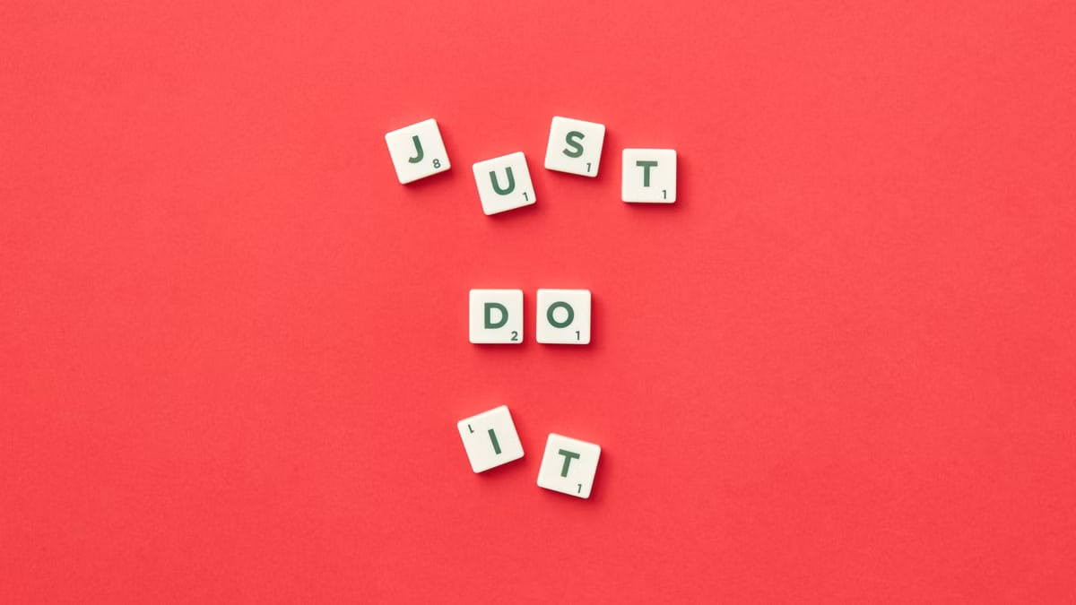 Motivational phrase 'Just Do It' spelled with Scrabble letters on a red background.